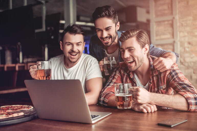 Männer beim Online Bier Tasting vor dem Laptop